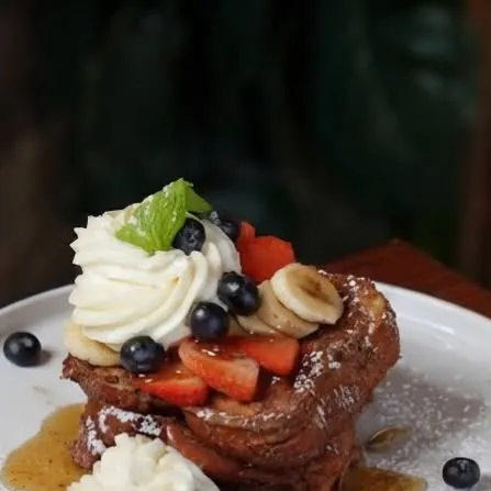 Pan francés con crema batida, fresas y moras azules.